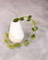 White ceramic teardrop-shaped planter with green vine on a gray background