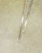 Two clear crystal sticks on a textured beige surface